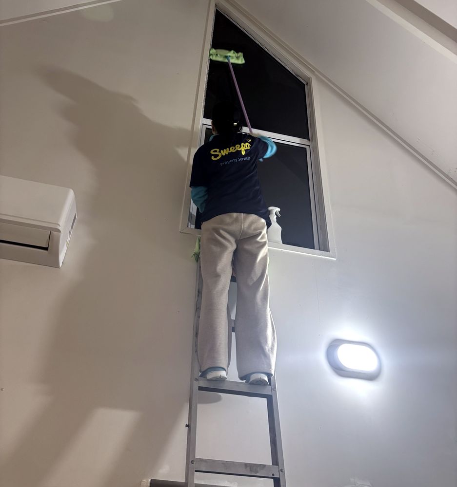 Sweepo cleaner on a ladder cleaning a high gable window